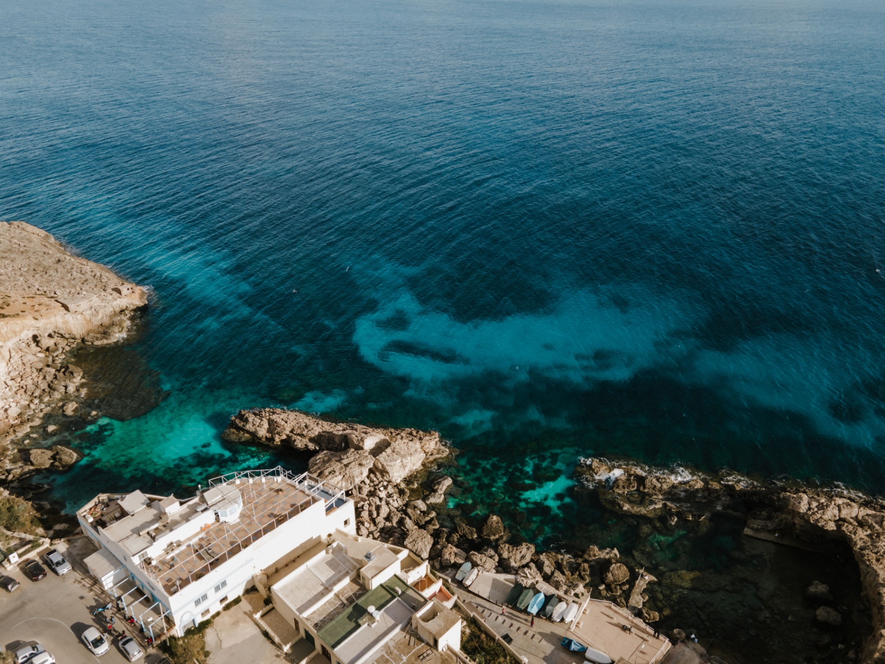 Aerial view of Malta's turquoise coastline with cliffside buildings